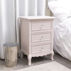 a white dresser sitting next to a bed in a bedroom