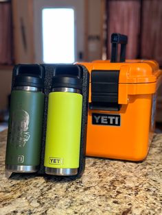 two yeti bottles sitting on top of a counter next to an orange cooler box