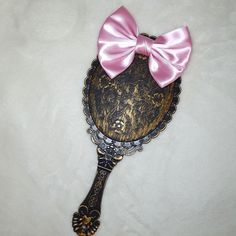 a hairbrush with a pink bow on it's head sitting on a white surface