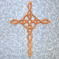 a cross made out of wood sitting on top of a blue surface with an intricate design