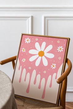 a pink and white painting sitting on top of a wooden chair