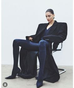 a woman sitting in a chair with her legs crossed and wearing high heeled boots