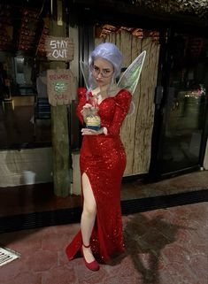 a woman dressed as tinkerbell holding a cupcake in front of a store