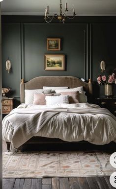 a bedroom with dark green walls and white bedding, chandelier above the bed