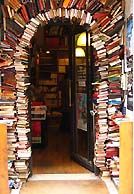 a room filled with lots of books next to a doorway covered in stacks of books