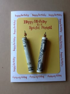 two rolled up money are sitting on top of a card with the words happy birthday written on it