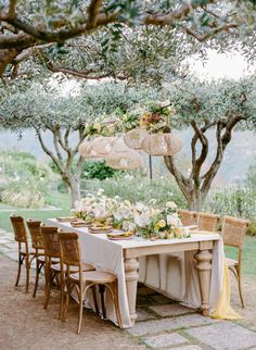 an outdoor dining table set up with flowers and umbrellas