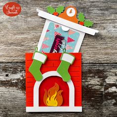 a christmas card with stockings and stockings hanging from the fireplace, on top of a wooden table