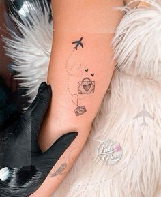 a woman's arm with a tattoo on it and an airplane flying over her head