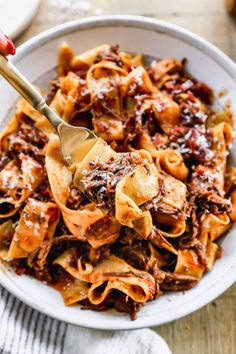 a white bowl filled with pasta and meat