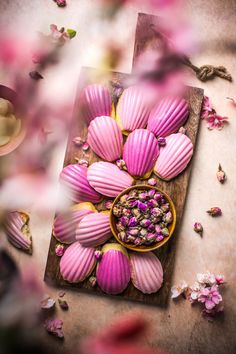 there are many pink flowers in the bowl on the table and petals scattered around it