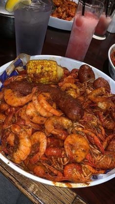 there is a large platter of shrimp and corn on the cob with drinks