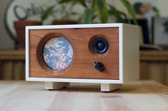 a wooden clock sitting on top of a table next to a plant in a pot