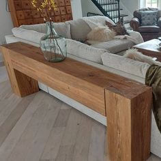 a living room filled with furniture and a wooden table in front of a couch on top of a hard wood floor