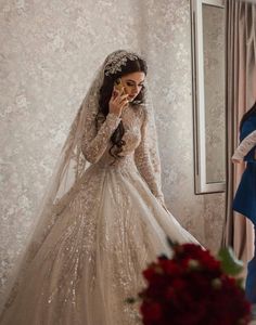 a woman standing in front of a mirror wearing a wedding dress and holding a cell phone to her ear