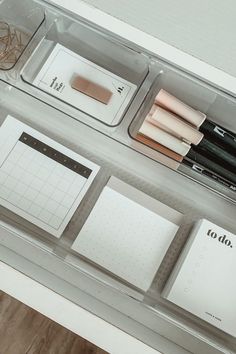 an organized drawer with pens, notebooks and other items