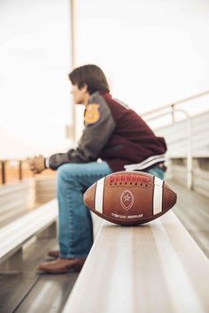 a football sitting on top of a wooden bench next to a person with a book