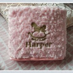 a close up of a pink blanket with a horse on it and the name harper