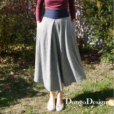 a woman standing in the grass with her hands on her hips, wearing a skirt