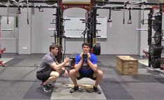 two men squatting down in a gym