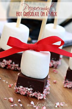 marshmallows on sticks tied with a red ribbon and placed on a wooden table