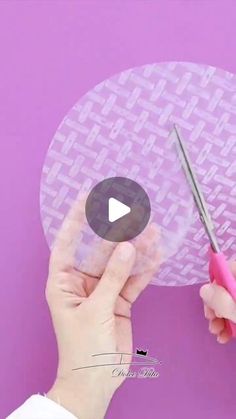 someone is cutting out the pattern on a paper plate with a pair of pink scissors