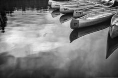 several canoes are lined up on the water's edge in black and white