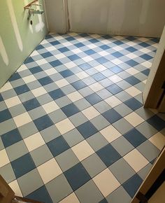 a bathroom with blue and white checkered flooring next to a toilet paper dispenser