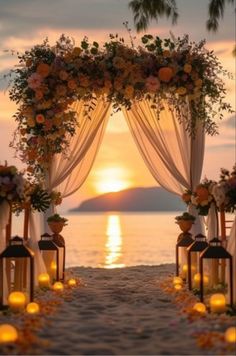 an outdoor wedding set up with candles and flowers on the beach at sunset or sunrise