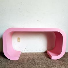 a pink shelf sitting on top of a carpeted floor next to a white wall