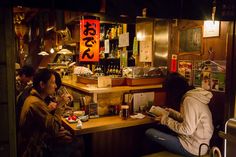 two people sitting at a bar in a restaurant