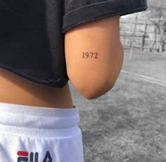 a person with a small tattoo on their left arm and the word 1932 written in black ink