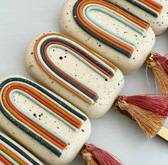 four handmade soaps with tassels are lined up on a white surface