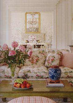 a living room filled with lots of furniture and flowers on top of a coffee table