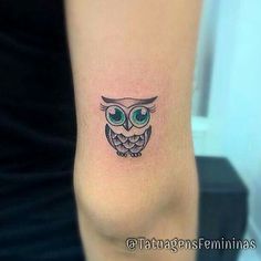 an owl tattoo on the arm with green eyes and big ears is seen in this image