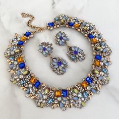 Colourful Necklace & Earring Set Our royal blue with golden yellow and multi-coloured jewels rhinestone necklace and earring set is perfect for a special event or as a gift to a loved one.  This blue rhinestone bib necklace and matching earrings are made up of stunning blue, golden yellow and multi-coloured jewels and perfectly placed within an antique gold base. The matching earrings are available in two styles to suit all preferences, a smaller stud earring or a drop and dangle earring.  Makes Contrast Jewellery, Blue Lehenga, Gold Statement Necklace, Small Earrings Studs, Necklace And Earring Set, Jewellery Set, Rose Gold Jewelry, Colourful Necklace, Rhinestone Jewelry