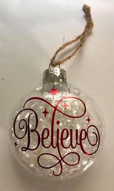 a glass ornament with the word believe written in red and white on it