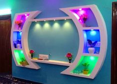 a room with blue walls and colorful lights on the wall, along with shelves that have flowers in them