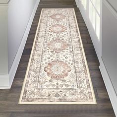 a hallway with a rug on the floor next to an open door and white walls