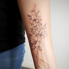 a woman's arm with flowers on it and a black ink tattoo that reads,