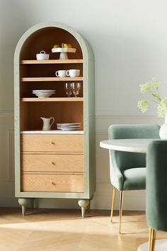 a wooden cabinet sitting next to a table with plates and cups on top of it