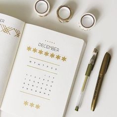 an open planner with gold stars on it next to some pens and pencils, along with other office supplies