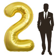 a man in a suit and tie standing next to a balloon shaped like the number two