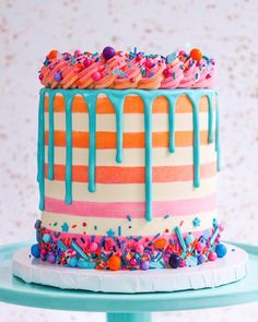 a multicolored cake with sprinkles and icing on a table