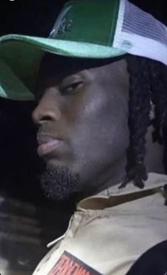 a close up of a person wearing a hat and looking off to the side with dreadlocks