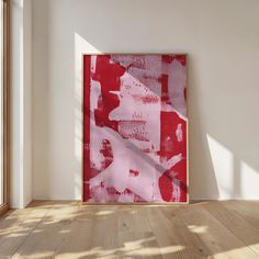 a red and white abstract painting on a wall in an empty room with wooden floors