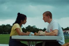 a man and woman sitting at a picnic table