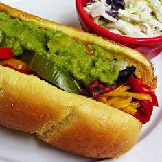 a hot dog on a plate with coleslaw and guacamole