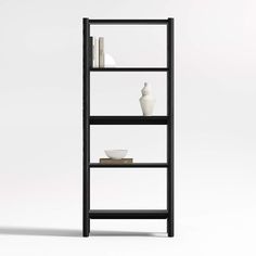 a black shelf with two white vases on top of it and bookshelves in the background