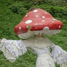 a woman in white dress standing next to a red mushroom